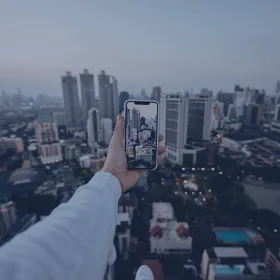 A man taking pictures of the city sitting on the roof