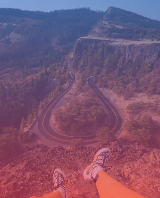 A man sits on top overlooking a winding road